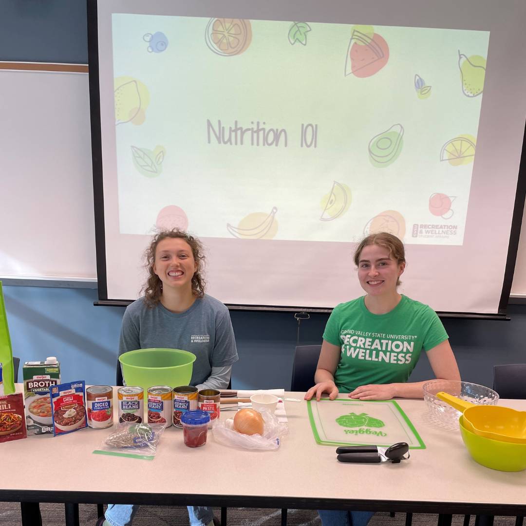 Two WIT peer educators in front of Nutrition 101 presentation doing a food demo